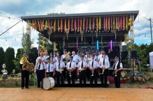 Orkiestra Dęta Zaburze na tle sceny podczas uroczystości jubileuszowych z okazji 100-lecia działalności