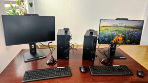 Dwa stanowiska komputerowe z monitorami, komputerami stacjonarnymi, kamerami internetowymi, klawiaturami, mikrofonami i myszami